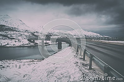 Vintage image of winter road and bridge between Lofoten Islands, moody dramatic landscape Stock Photo