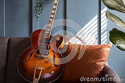 Vintage jazz guitar against a blue wall in natural light Stock Photo