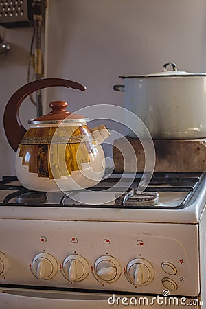 Vintage kettle and soup pan on gas stove. Retro kitchenware in village. Rustic household equipment. Stock Photo