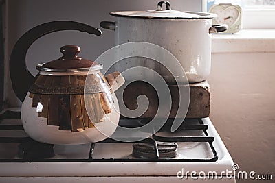 Vintage kettle and soup pan on gas stove. Retro kitchenware in village. Rustic household equipment. Stock Photo