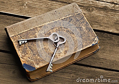 Vintage keys lying on shabby battered old book Stock Photo