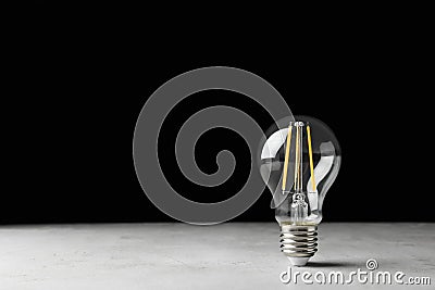 Vintage lamp bulb on light table against black background Stock Photo