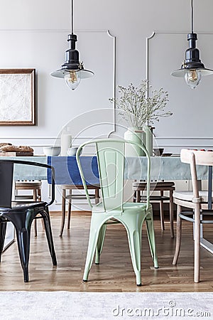 Vintage lamps and green chair at the table in a simple dining room interior. Real photo Stock Photo