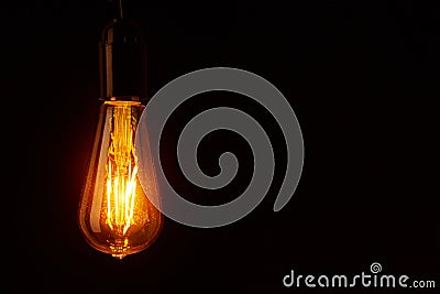 Vintage light bulb on black background, copy space. Glowing edison bulb Stock Photo