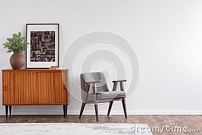 Vintage living room interior with retro furniture and poster, real photo with copy space on the white wall Stock Photo