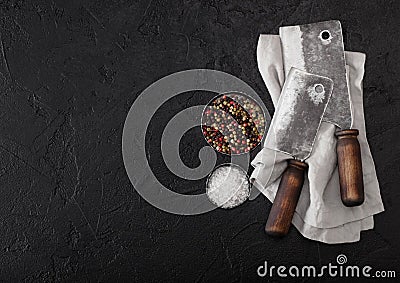 Vintage meat knife hatchets on kitchen towel and black stone table background. Butcher utensils. Salt and pepper Stock Photo