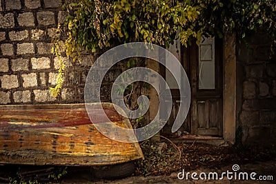 Vintage medieval building exterior on backyard with overturned old vintage sail boat in overcast day during raining autumn season Stock Photo