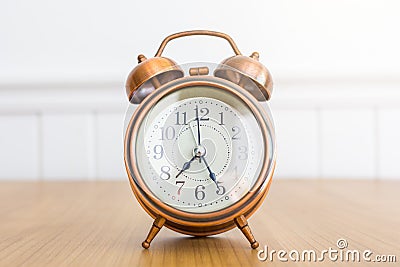 Vintage metalic alarm clock on wooden table over white wall background Stock Photo