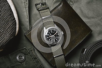 Vintage military watch with nato strap and leather wallet on army green background, Classic timepiece mechanical wristwatch Stock Photo