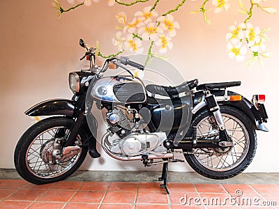 16 ,Dec 2011 : Vintage motorcycle standing in front of Plumeria flower wall, Side view, Pattaya, Thailand Editorial Stock Photo