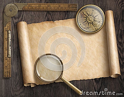 Vintage nautical compass and loupe on table with treasure map scroll Stock Photo