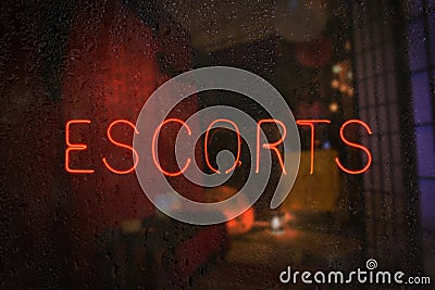 Vintage Neon Sign in Wet Rainy Window Escorts Stock Photo