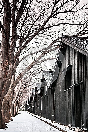 Vintage old Japanese black warehouse in winter snow and tree lin Stock Photo