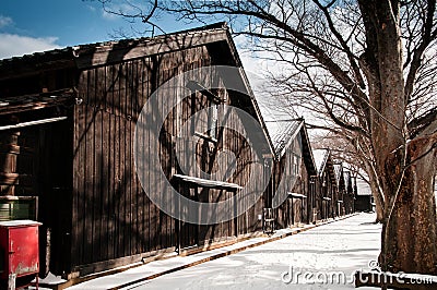 Vintage old Japanese black warehouse in winter snow and tree lin Stock Photo