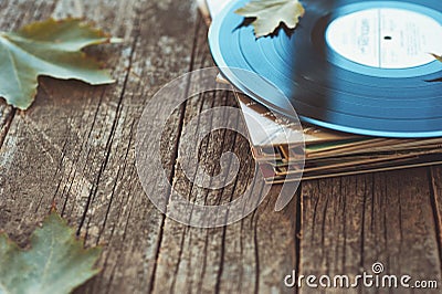 Vintage old vinyl records on wooden autumn background, selective focus decorated with few leaves. Music, fashion, texture, Stock Photo