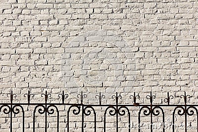 Vintage openwork forged fence on the background of the light brick wall of the house. Stock Photo