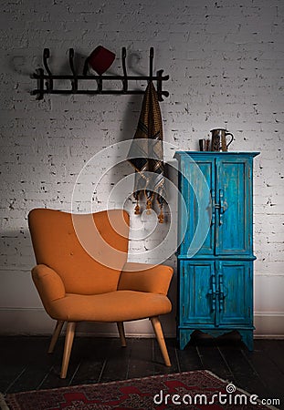 Vintage orange armchair, blue cupboard, wall hanger and black scarf Stock Photo