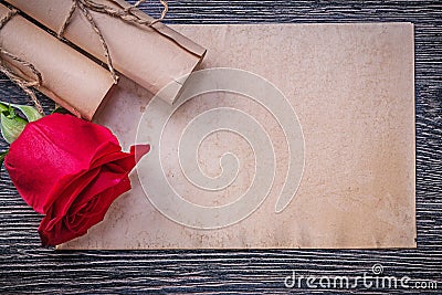 Vintage paper rolls red scented rose on wooden background Stock Photo