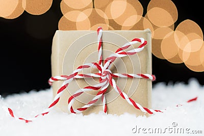 Vintage paper wrapped gift with red and white twine on snow Stock Photo