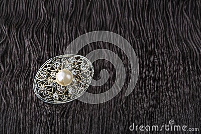 Vintage pearl jewelry brooch on little black dress. Gatsby or Chicago fashion look. Getting ready for party. Elegant gift for Stock Photo