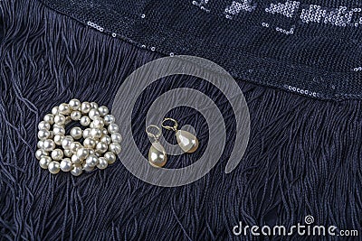 Vintage pearl jewelry on little black dress. Gatsby or Chicago fashion look. Luxury white necklace and earrings. Getting ready for Stock Photo