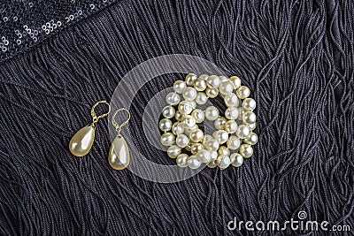 Vintage pearl jewelry on little black dress. Gatsby or Chicago fashion look. Luxury white necklace and earrings. Getting ready for Stock Photo