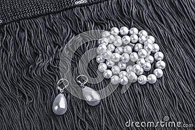 Vintage pearl jewelry on little black dress. Gatsby or Chicago fashion look. Luxury white necklace and earrings. Getting ready for Stock Photo