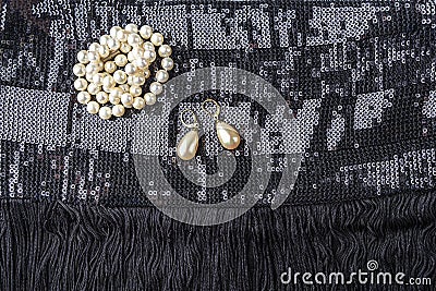 Vintage pearl jewelry on little black dress. Gatsby or Chicago fashion look. Luxury white necklace and earrings. Getting ready for Stock Photo