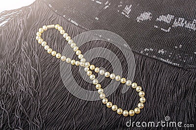 Vintage pearl jewelry on little black dress. Gatsby or Chicago fashion look. Luxury white necklace. Getting ready for party. Stock Photo