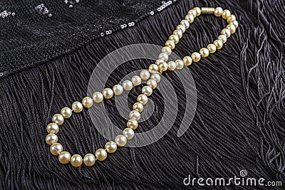 Vintage pearl jewelry on little black dress. Gatsby or Chicago fashion look. Luxury white necklace. Getting ready for party. Stock Photo