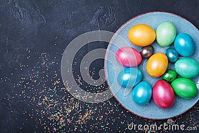 Vintage plate with colorful eggs on black table top view. Easter background. Stock Photo