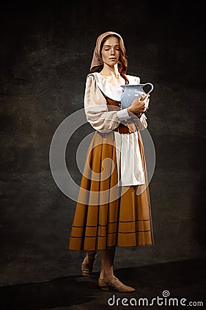 Vintage portrait of young adorable redhead girl in image of medieval person in renaissance style dress on dark Stock Photo