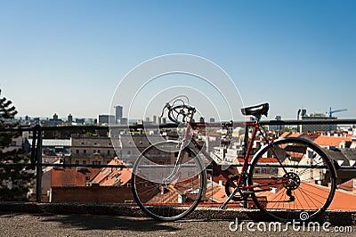 Vintage red city bicycle locked to the metal fence with view over Zagreb. Old red road bicycle. Stock Photo