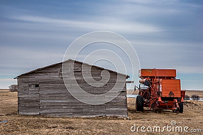 Vintage red combine abandoned beside an old barn in Saskatchewan, Canada Stock Photo