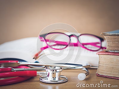 Vintage retro of books, a stethoscope glasses and pencil on a wooden desk Stock Photo
