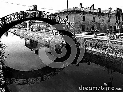 Vintage retro effect view of an old bridge over Naviglio Pavese in Milan with ancient houses on the background - black and white Stock Photo