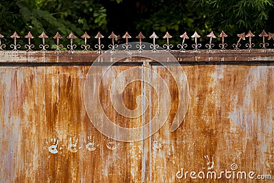 A vintage rusted steel gate on permanent closing and becoming fence. The steel gate has some palm mark on the surface. The palm ar Stock Photo