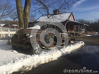 Vintage rusted truck makes rustic firewood stand next to red barn Stock Photo