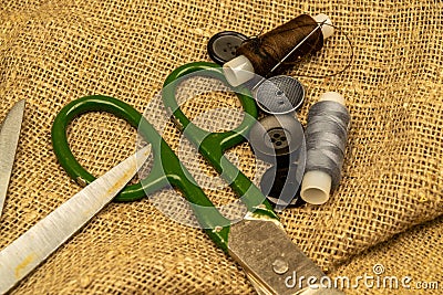 Vintage sartorial scissors lying on rough fabric with buttons and threads Stock Photo