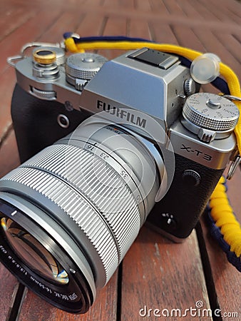 Vintage silver and black Fujifilm camera with brown leather strap on wooden table. Copy space for text. Antique, photography Editorial Stock Photo