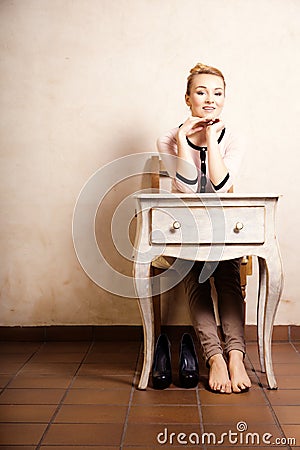 Vintage style. Barefoot girl sitting at retro desk Stock Photo
