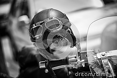 Vintage style motorbike helmet with goggles on the motorcycle handlebar. In Black and White Stock Photo