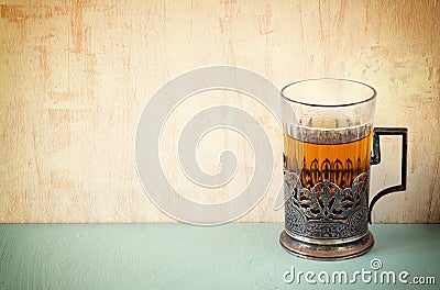 Vintage tea glass-holder over wooden table. retro filtered image Stock Photo