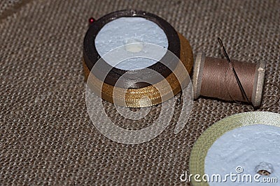 vintage threads on wooden spools and needle of beige color against a light Broun background Stock Photo