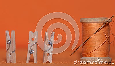 vintage threads on wooden spools of orange color against a light terracotta background Stock Photo