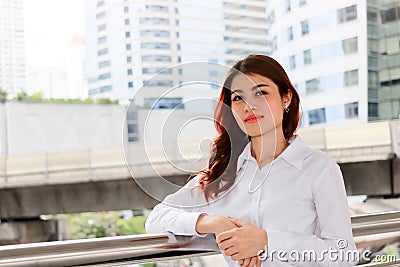 Vintage toned image of confident young Asian woman with white shirt at urban building public background. Stock Photo