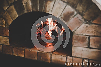 The vintage traditional oven makes from brown bricks with flame and firewood for cooking or baking pizza or yummy bread when the Stock Photo