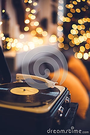vintage vinyl record player in a cozy home livingroom with lots of warm fairy lights and orange pillows couch Stock Photo