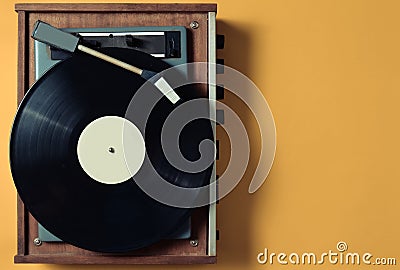 Vintage vinyl turntable with vinyl plate on a yellow pastel background. Entertainment 70s. Listen to music. Stock Photo