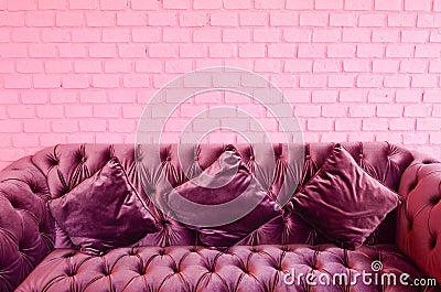 Vintage violet sofa with pink brick wall Stock Photo